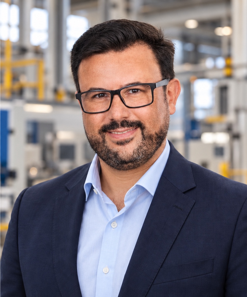 Retrato de Michel com terno azul-marinho e camisa azul-clara em ambiente industrial.